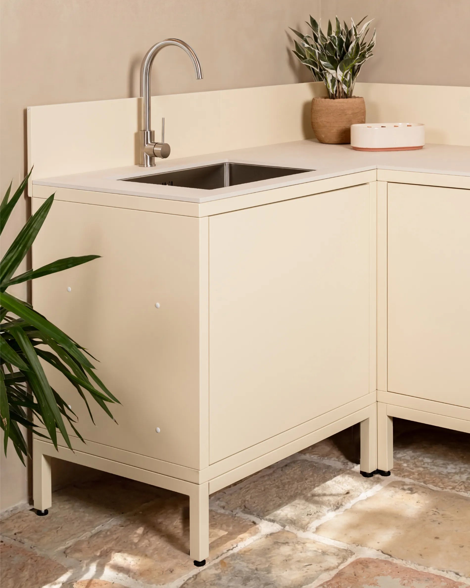 Beigefarbene PILOTIS-Unterkonstruktion unter Eckspülenschrank, Outdoor-Küche mit Wasserhahn und Pflanze