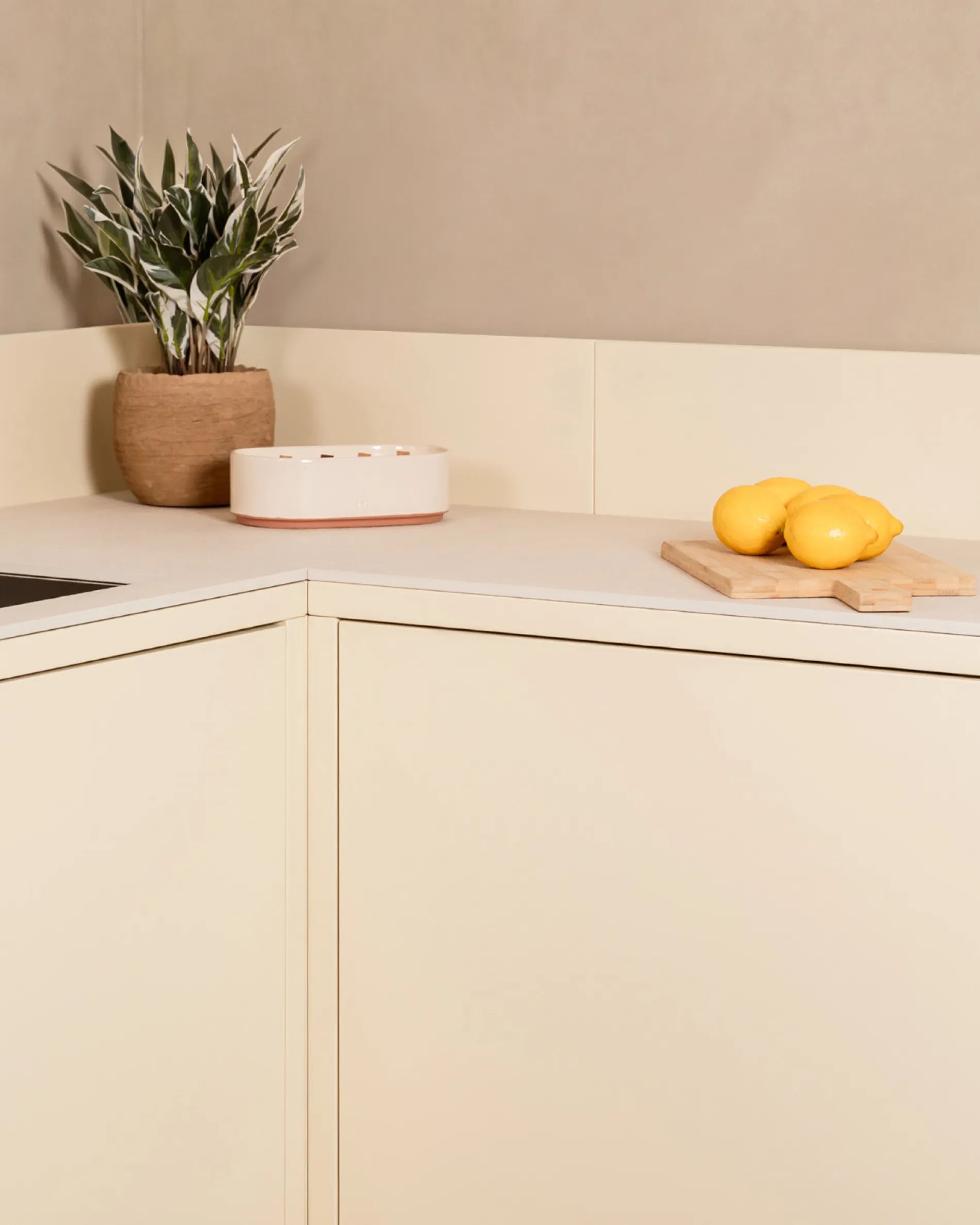 Eckmodul PILOTIS in Creme-Beige für die Außenküche, mit Pflanze und Zitronen auf dem Brett