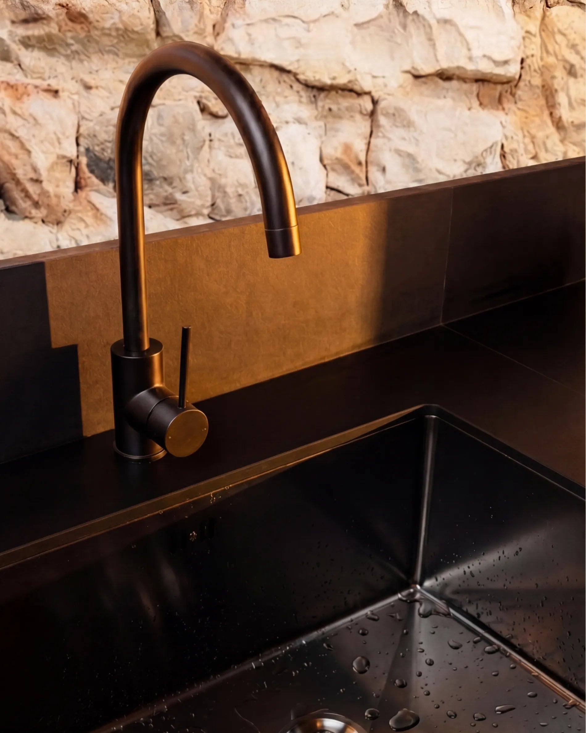 Schwarzes Waschbecken und Wasserhahn in Bronzeoptik des Spülmoduls PILOTIS, Nahaufnahme
