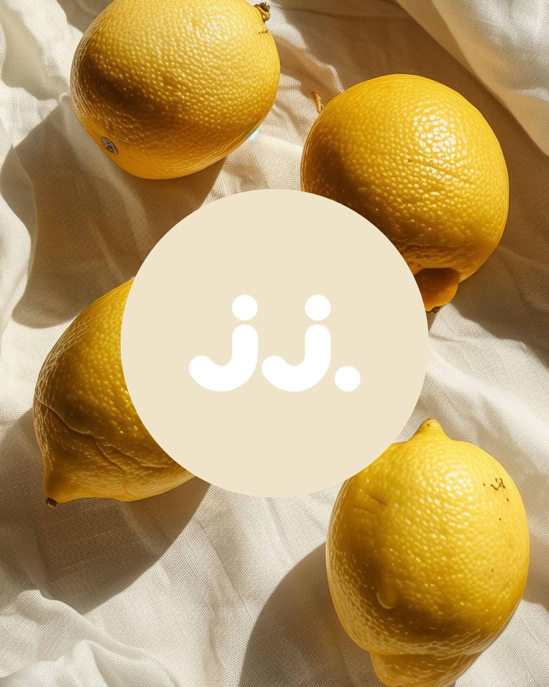 Gelbe Zitrone auf hellem Stoff mit jj.-Logo, inspiriert vom Duft Zitronengras & Zitrone.