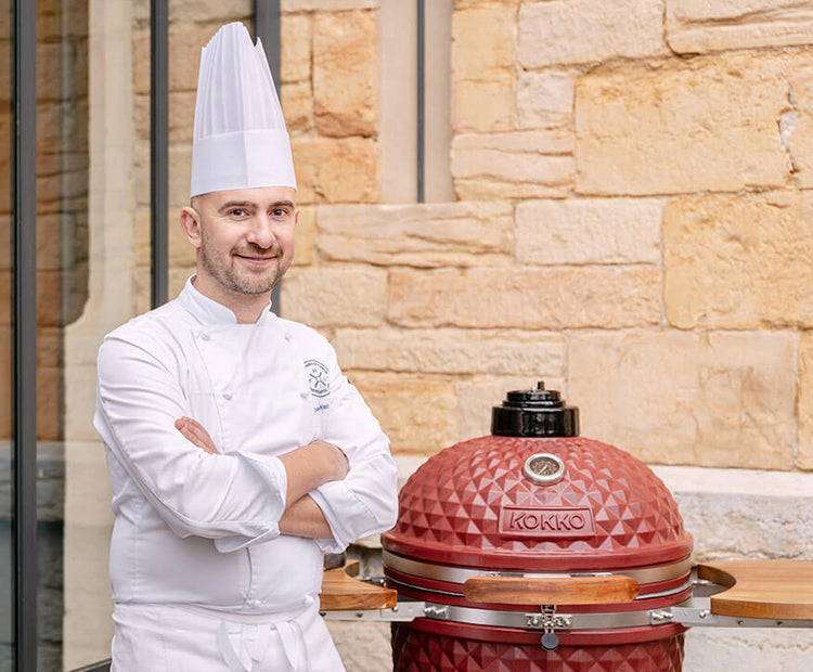 Chef cuisinant sur un kamado Kokko rouge lors d’une utilisation professionnelle.