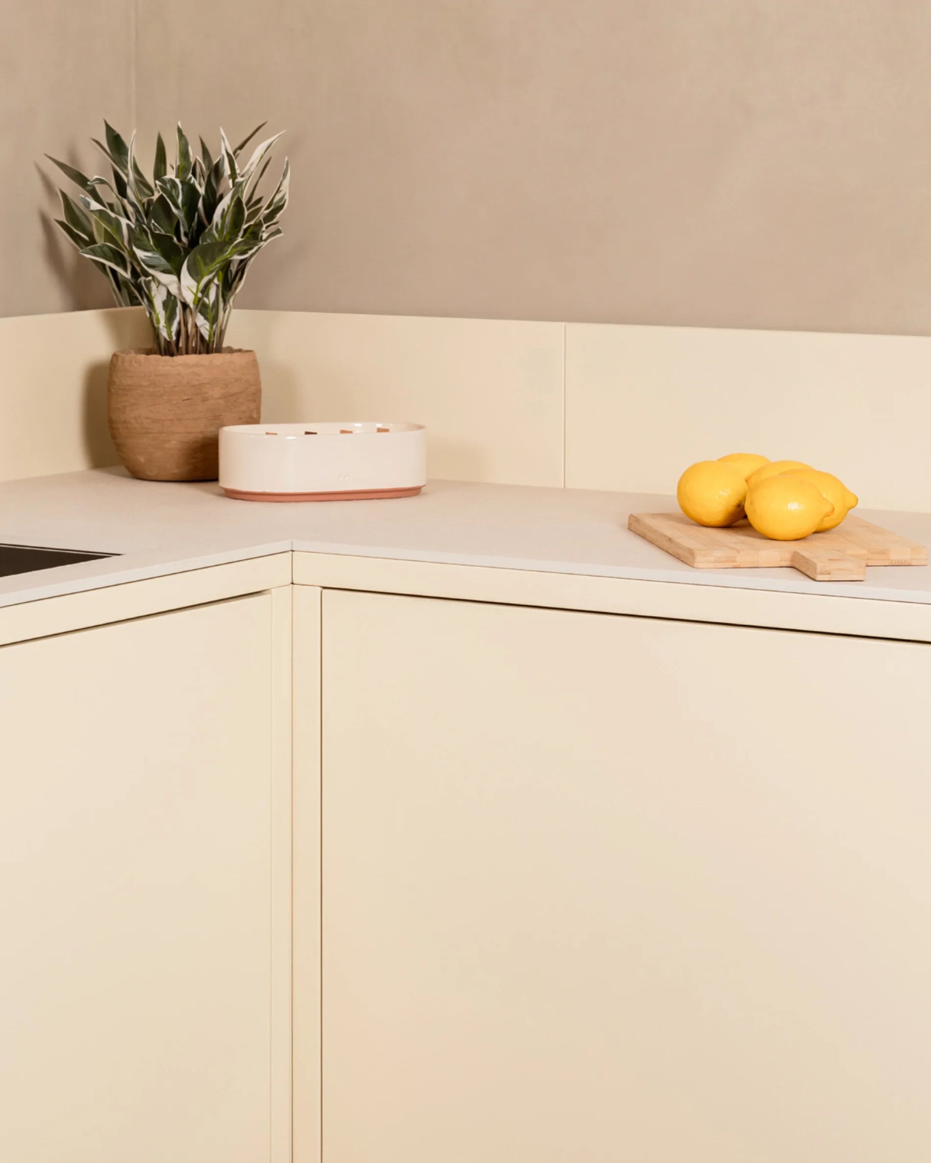 Detailansicht Ecke der Kokko Outdoor-Küche in Creme mit Arbeitsplatte und Pflanzendekoration