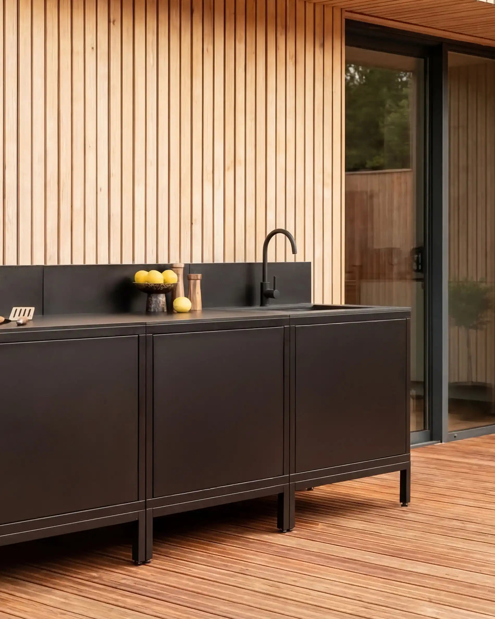 Cuisine extérieure Kokko noire design avec plan de travail et décorations.