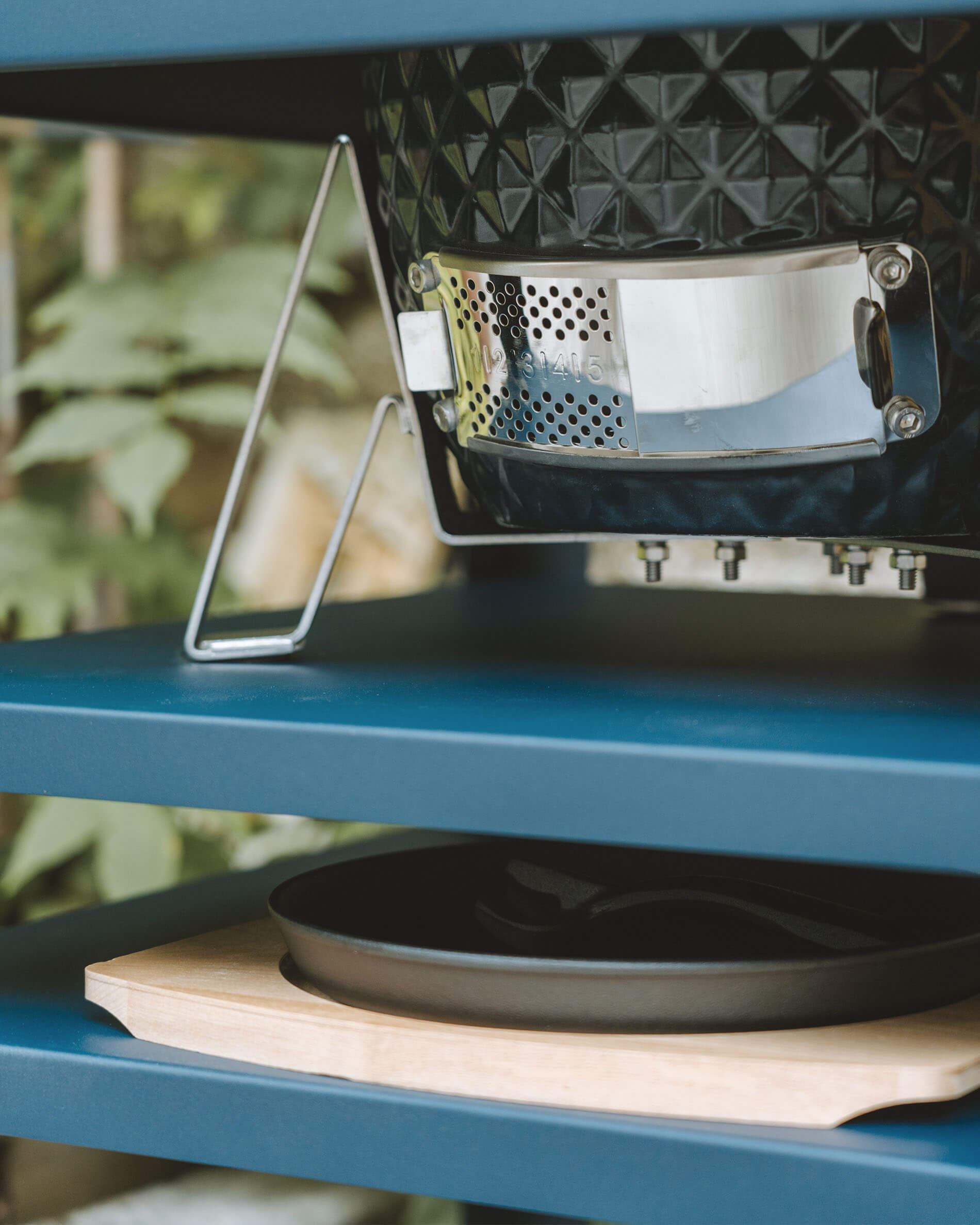 Detailansicht der unteren Belüftung aus Edelstahl eines Kokko Kamado, integriert in einen Metalltisch mit Ascheauffangbehälter.