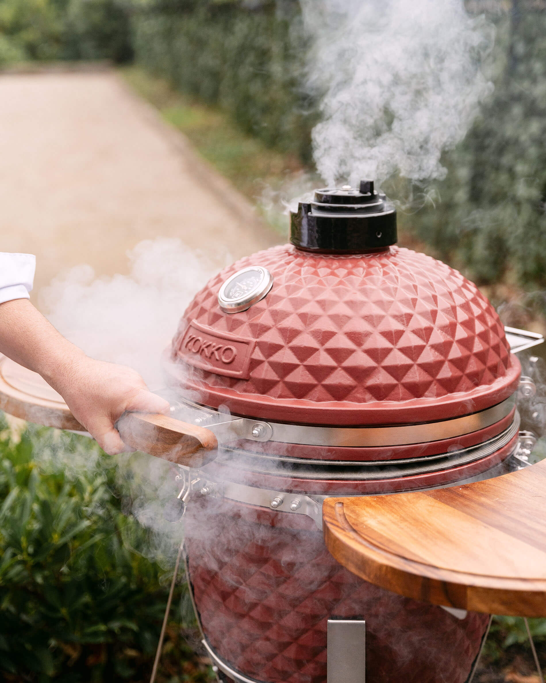 Kamado Kokko L 18 Zoll aus roter Oxid-Keramik mit aufsteigendem Rauch beim Grillen.