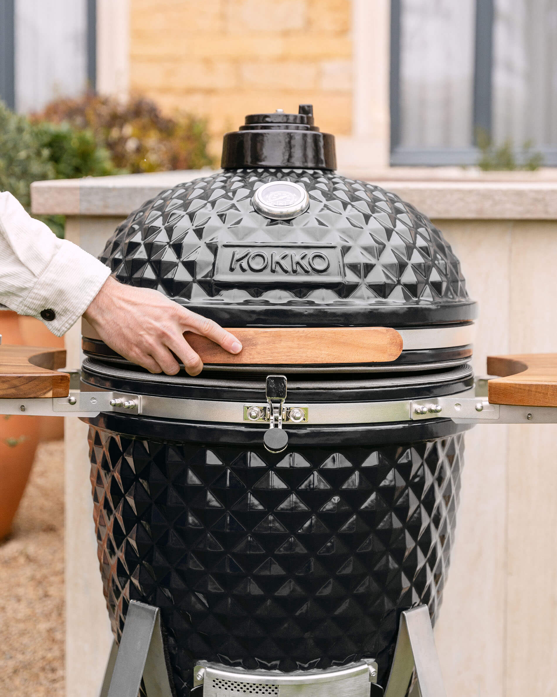 Kamado-Grill Kokko XL 22 Zoll aus schwarzer Keramik im Außenbereich installiert.