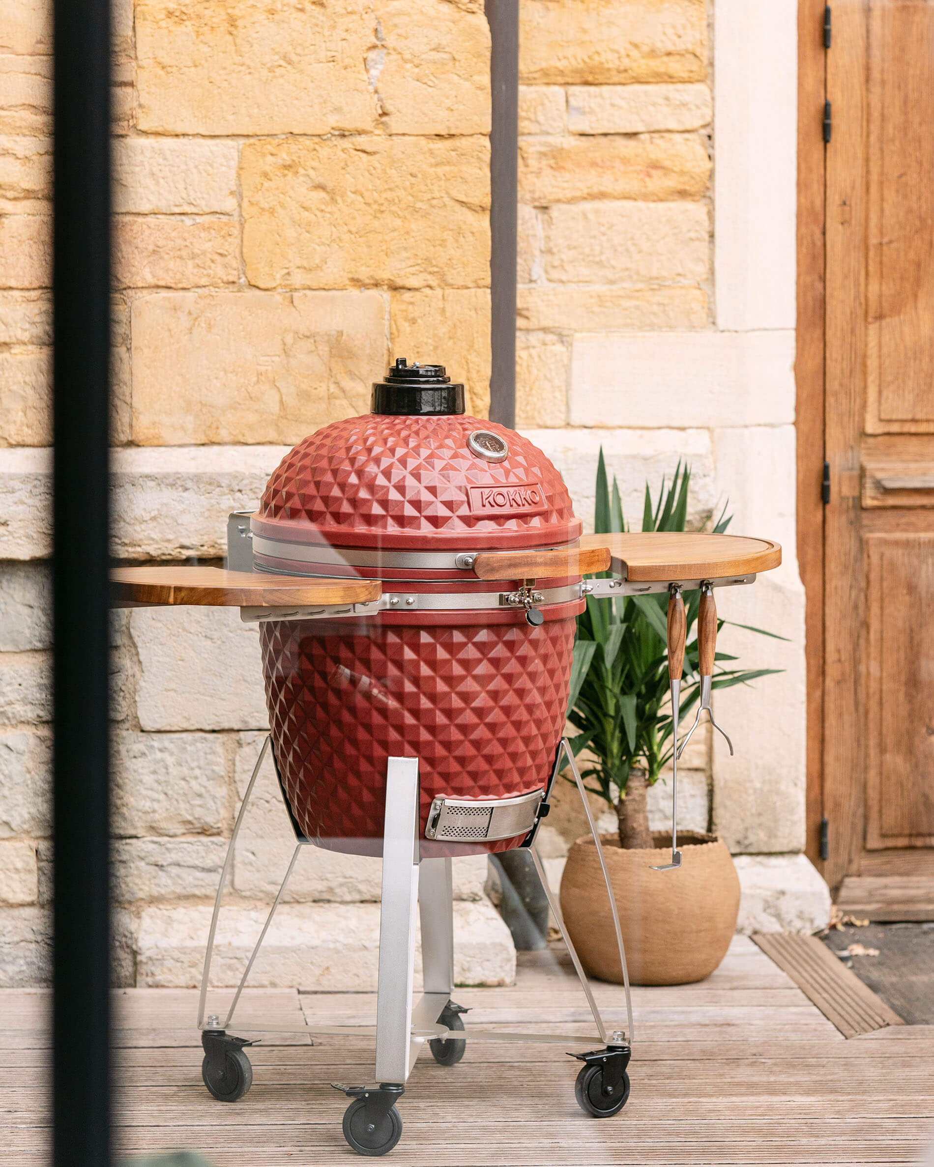 Kamado Kokko XL 22 Zoll aus roter Oxid-Keramik auf Wagen im Außenbereich.