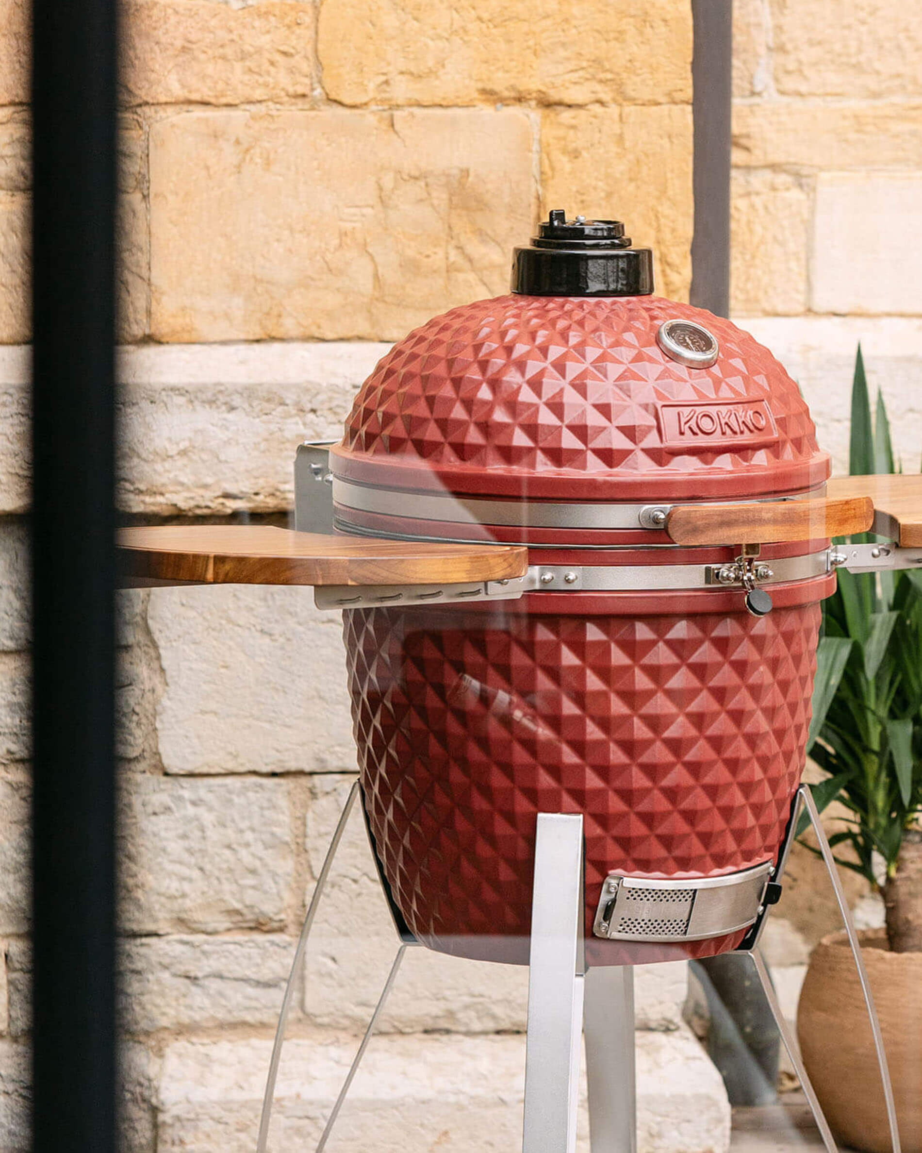 Kamado-Grill Kokko 22 Zoll in Oxidrot, einzeln im Außenbereich präsentiert.