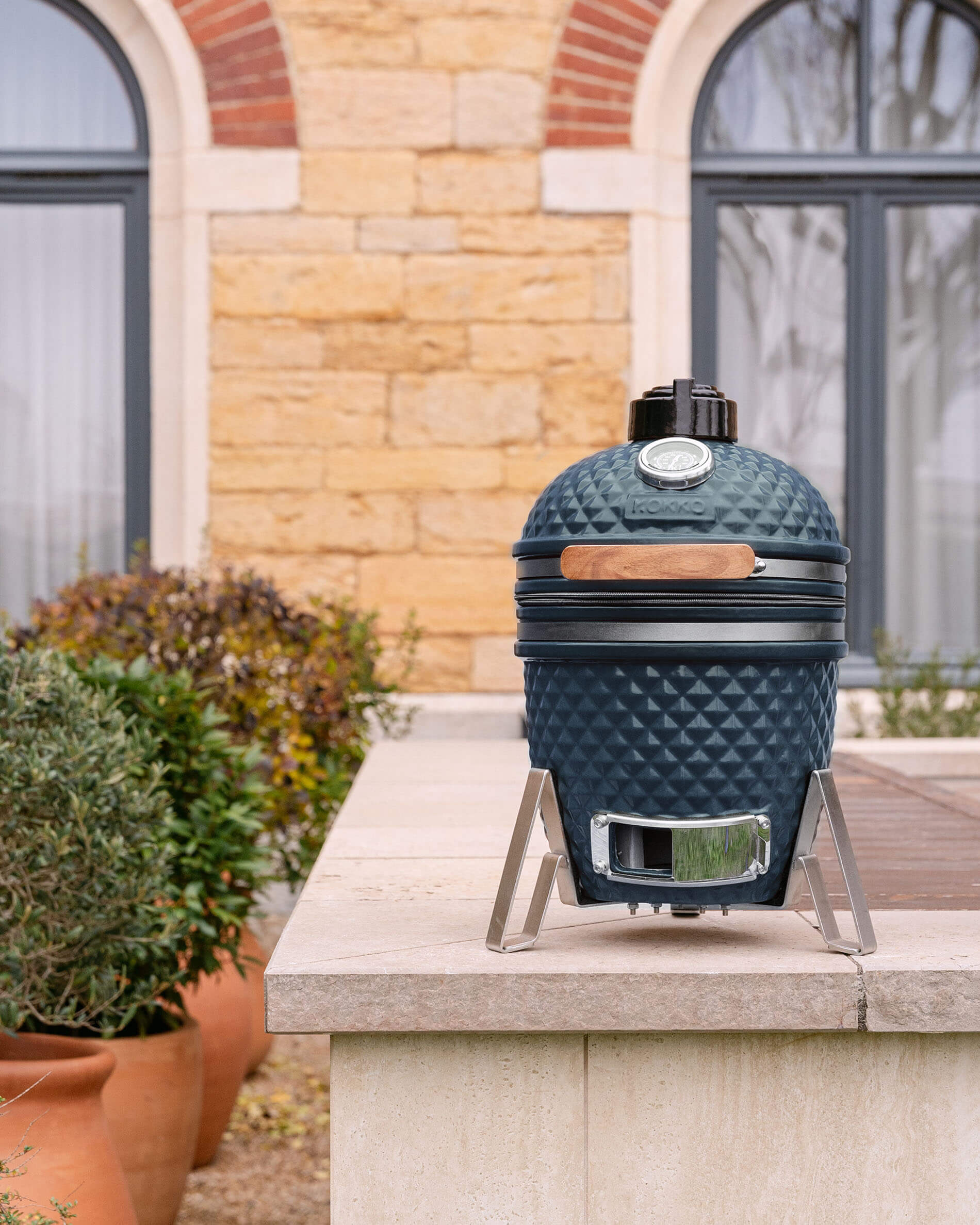 Kamado Little Kokko 13 aus blauer Keramik, im Außenbereich aufgestellt.