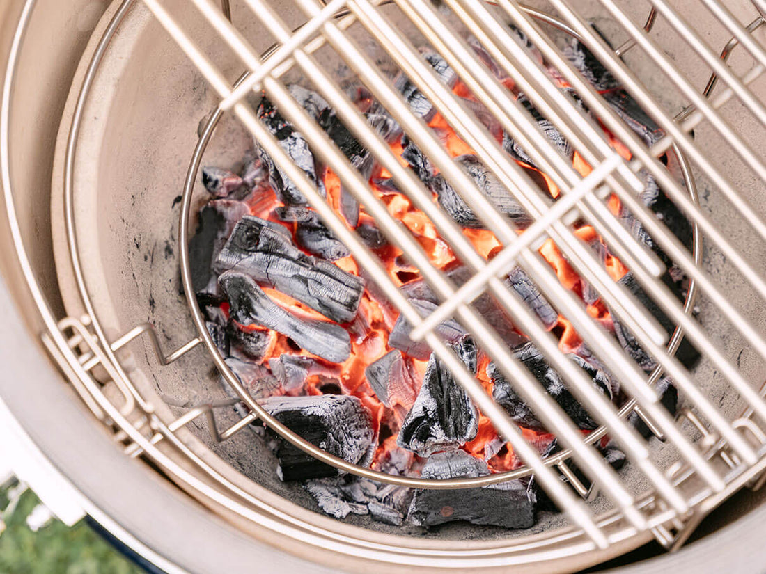 Glühende Holzkohle im Keramik-Korpus eines Kokko Kamado-Grills, mit sichtbaren roten Glutnestern unter dem Edelstahlrost – Sinnbild für das Anheizen und die präzise Kontrolle des Holzfeuers beim Grillen.