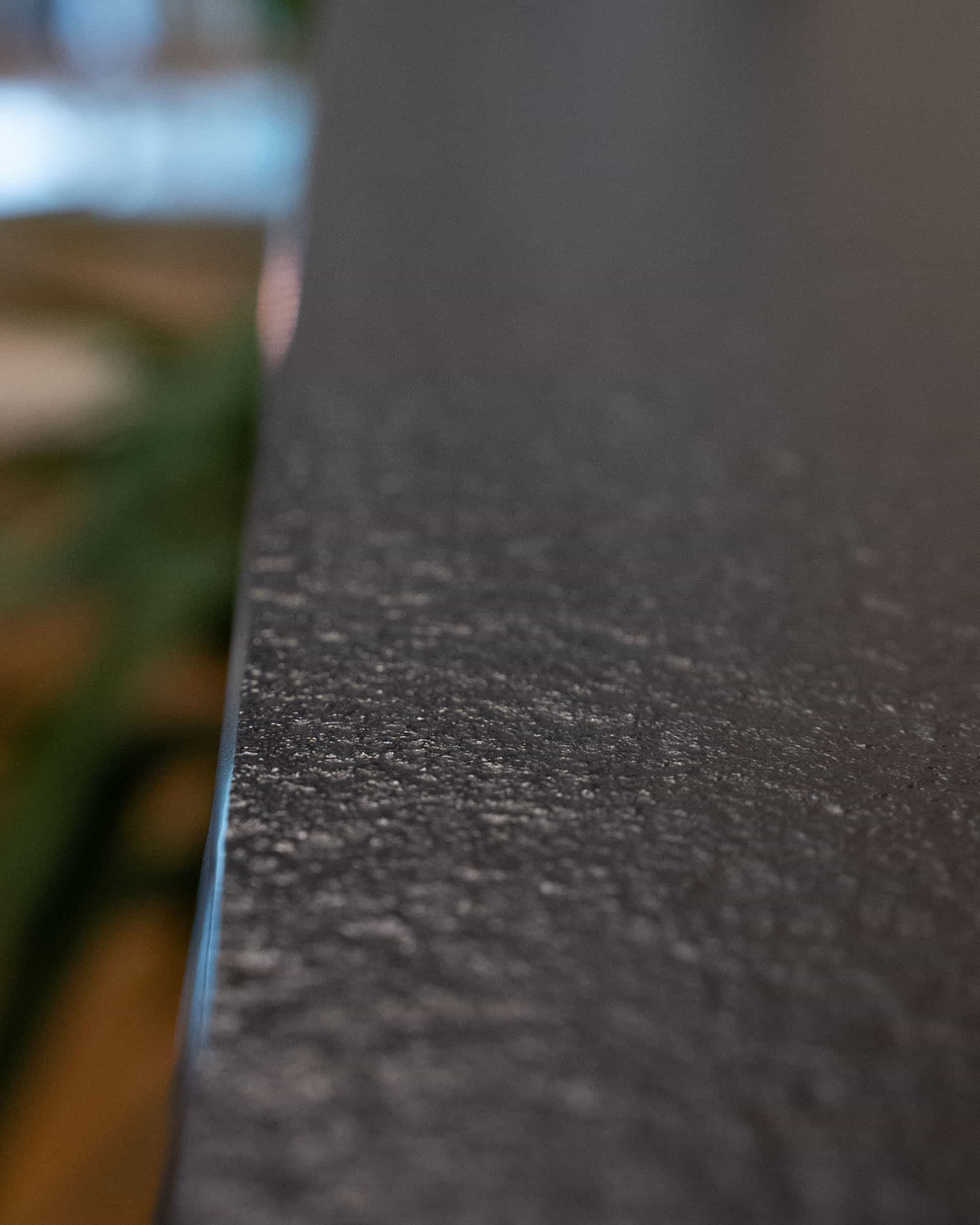 Detail einer Arbeitsplatte in einer Stelzenküche, mit sichtbarer Kante, matter Textur und hochwertiger Materialoberfläche.