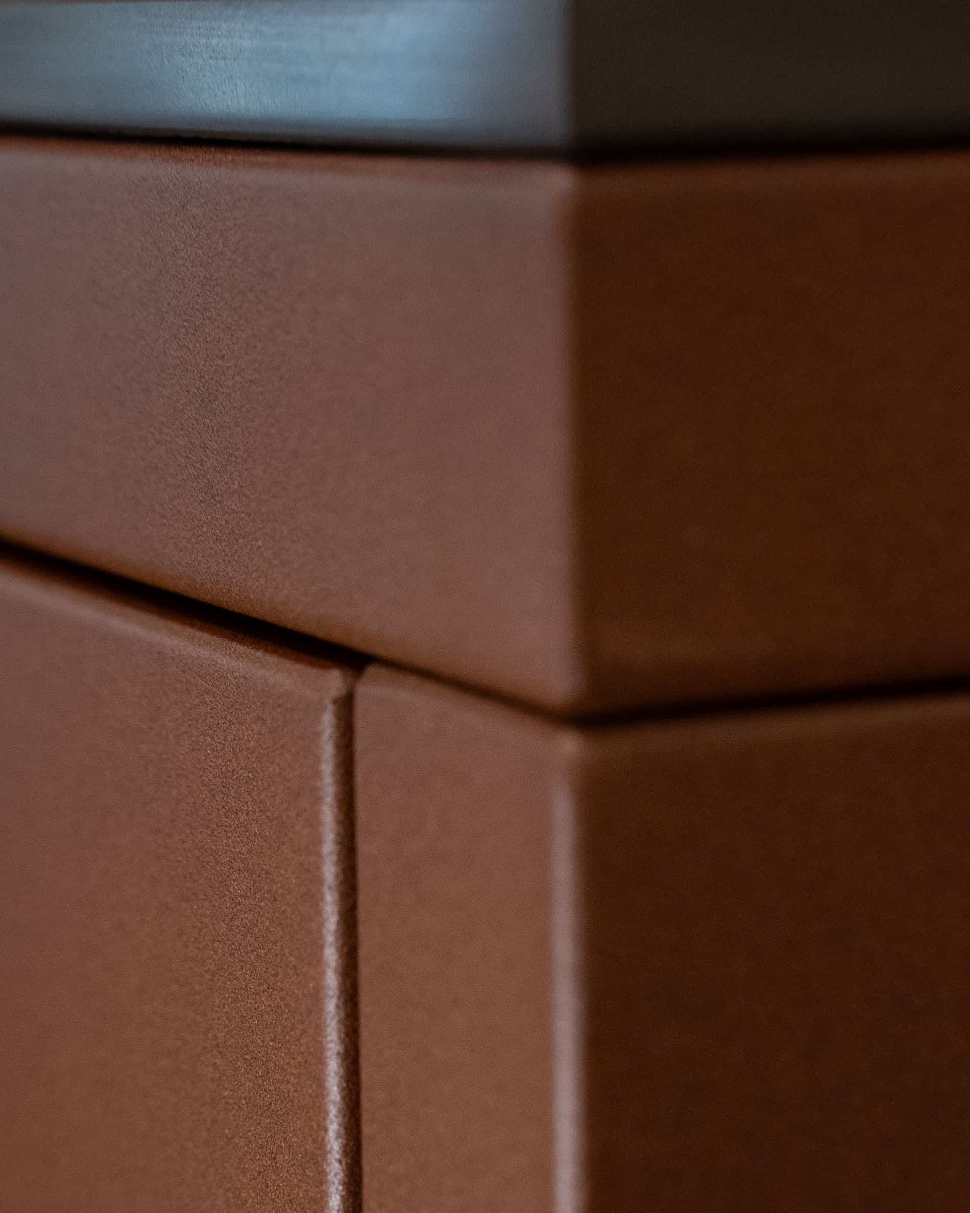 Detail einer Pilotis-Außenküche: Ecke des Möbels, präzise Verbindung der Paneele und matte Oberfläche in rostbrauner Farbe.