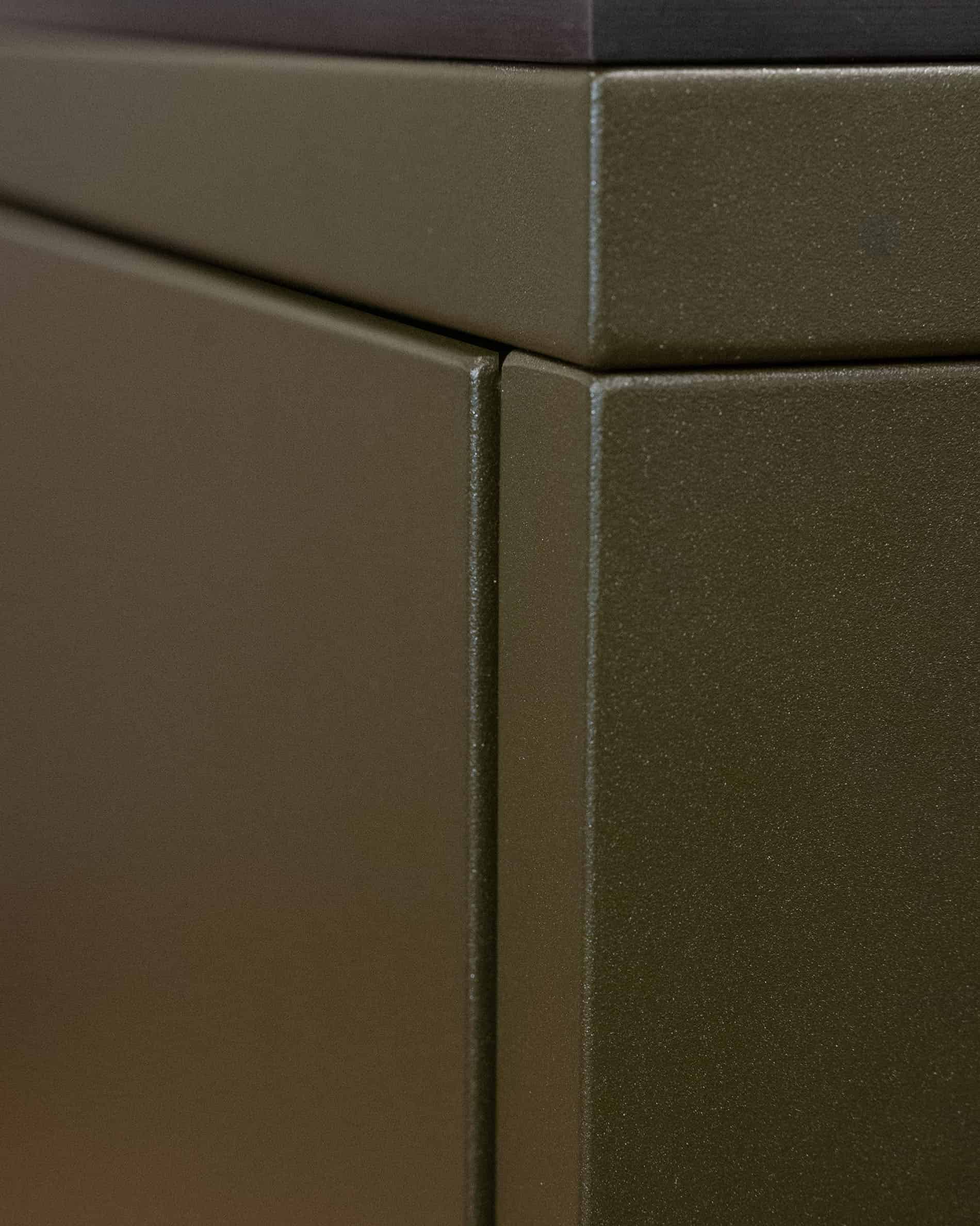 Detail einer Pilotis-Außenküche, zeigt die Verbindung der Metallpaneele und die olivfarbene Struktur der Front.