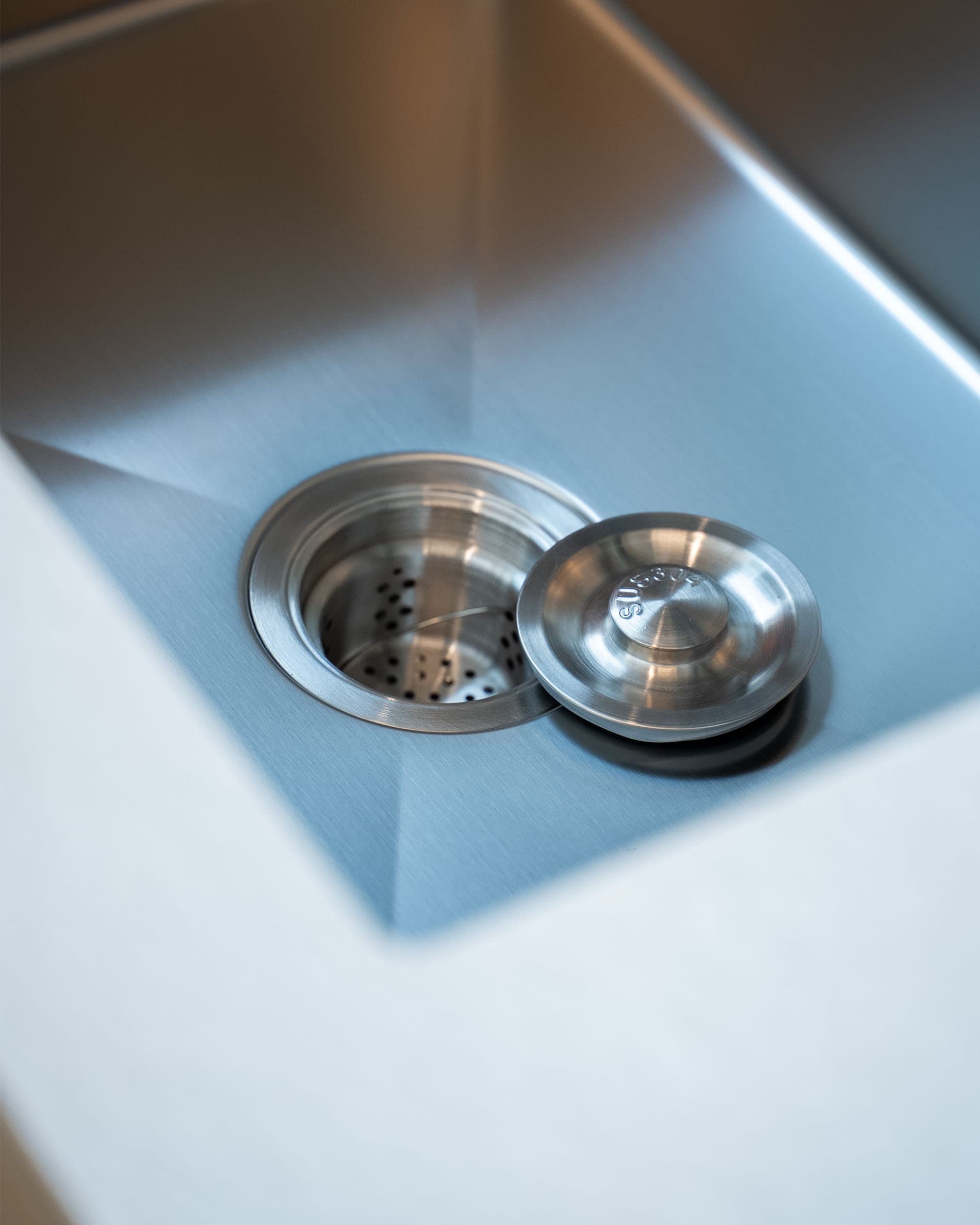 Detail des Spülbeckens einer Stelzenküche, mit Edelstahlbecken und integriertem Ablaufsystem.