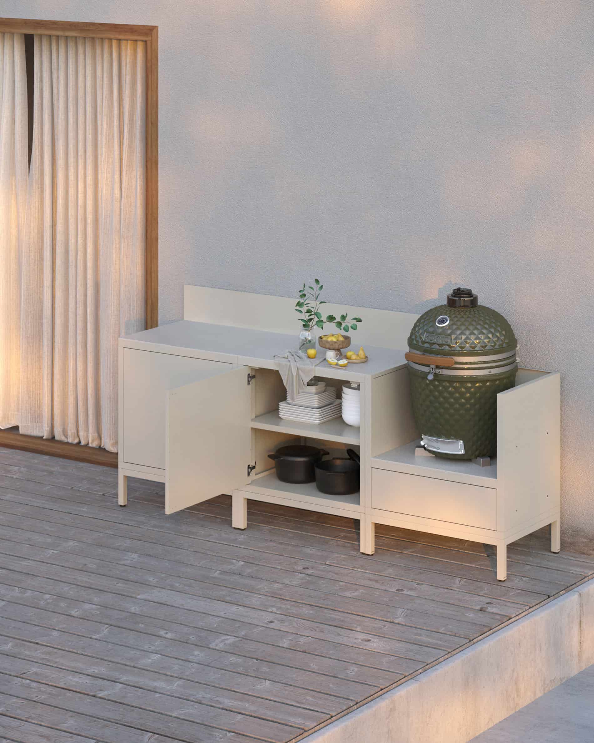 Outdoor-Küche auf Stelzen in Cremefarbe mit offenen und geschlossenen Stauräumen, heller Arbeitsplatte, passender Rückwand und integriertem Kamado-Modul auf erhöhter Struktur.