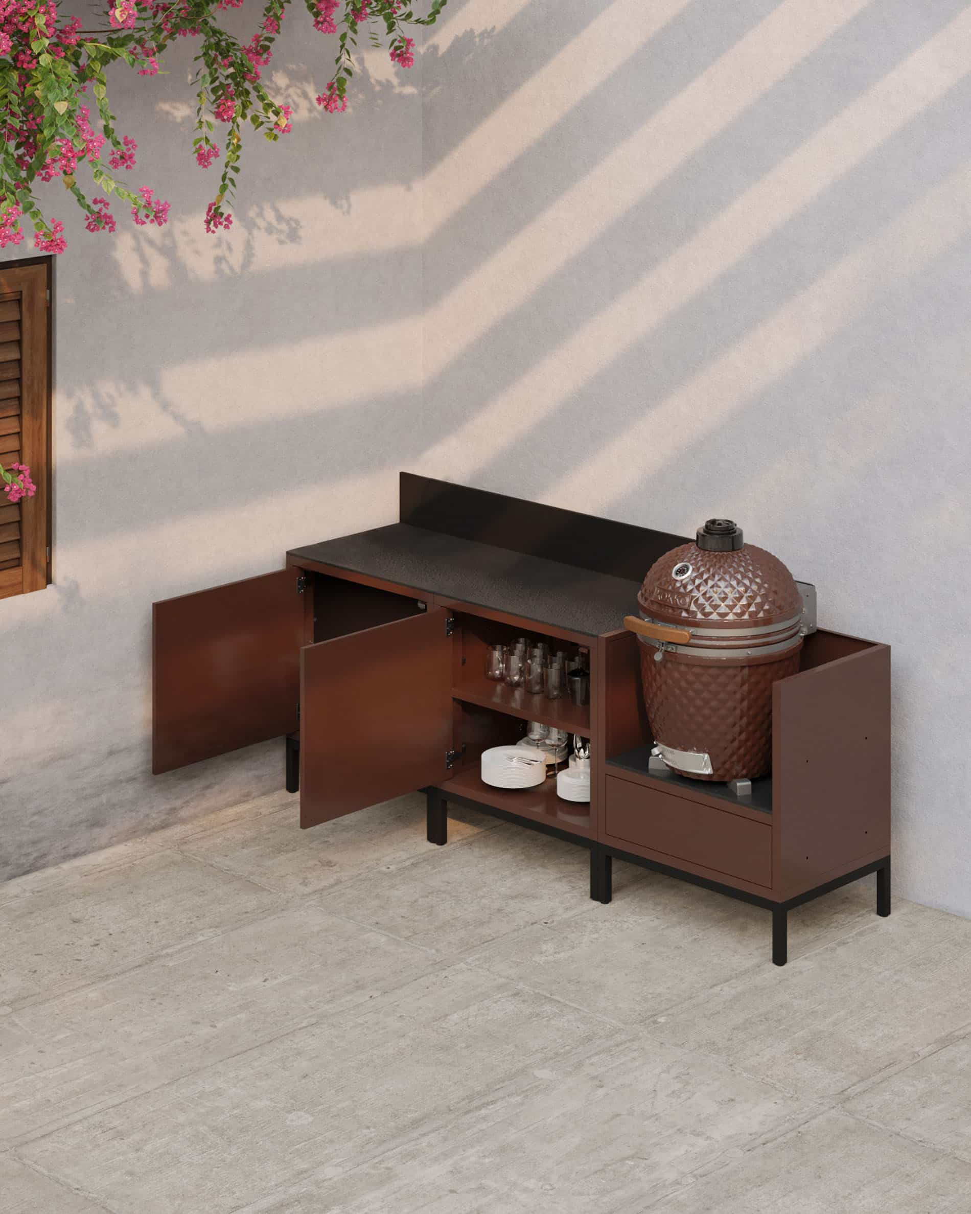 Outdoor-Küche auf Stelzen in Rostoptik mit offenen Türen, dunkler Arbeitsplatte, sichtbaren Innenfächern und integriertem Kamado-Modul für eine funktionale Außenküche.