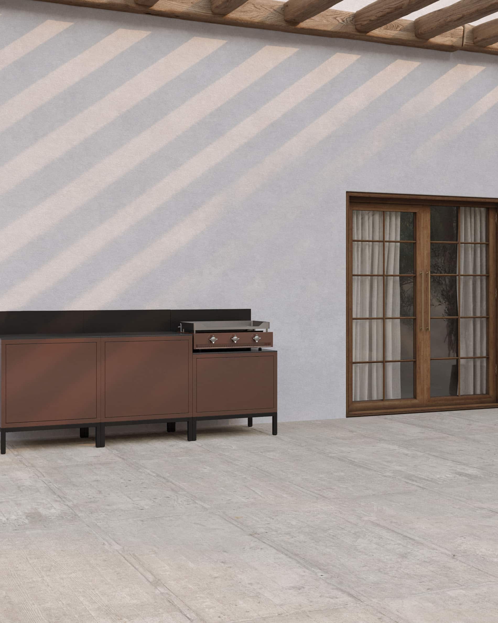 Outdoor-Küche auf Stelzen mit integrierter Plancha, Möbel in rostbrauner Farbe, geschlossene Stauräume und dunkle Arbeitsfläche, installiert auf einer überdachten Terrasse.