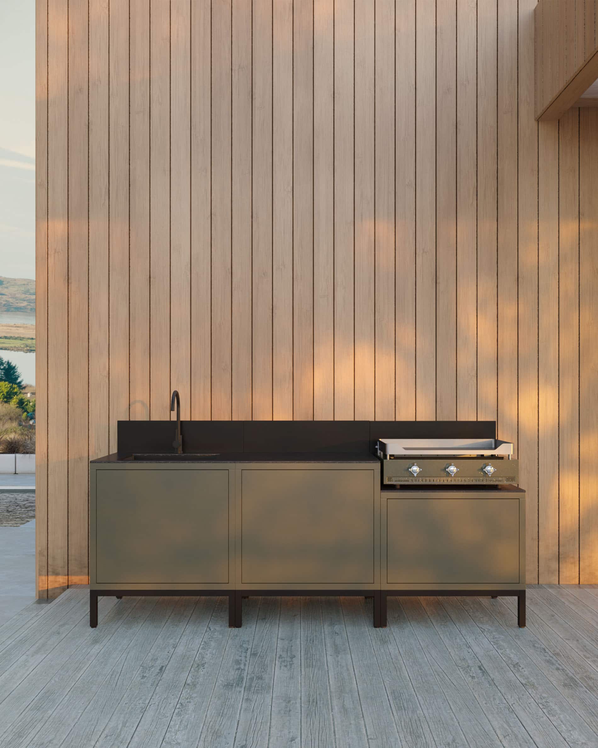 Kokko Outdoor-Küche mit integrierter Plancha, grünem Aufbewahrungsmöbel, Spüle und schwarzer Arbeitsplatte, auf einer Holzterrasse installiert.